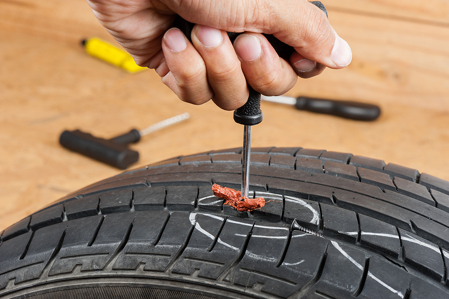 Mobile tire repair technician working on a car tire